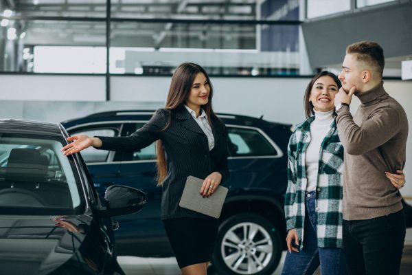Young couple choosing a car in a car show room